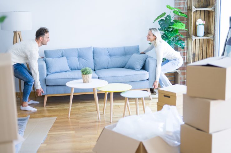 Una coppia che sposta il divano e mette in ordine il salone