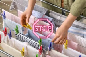 Una persona che appende il bucato sullo stendino ed un segnale di stop in primo piano