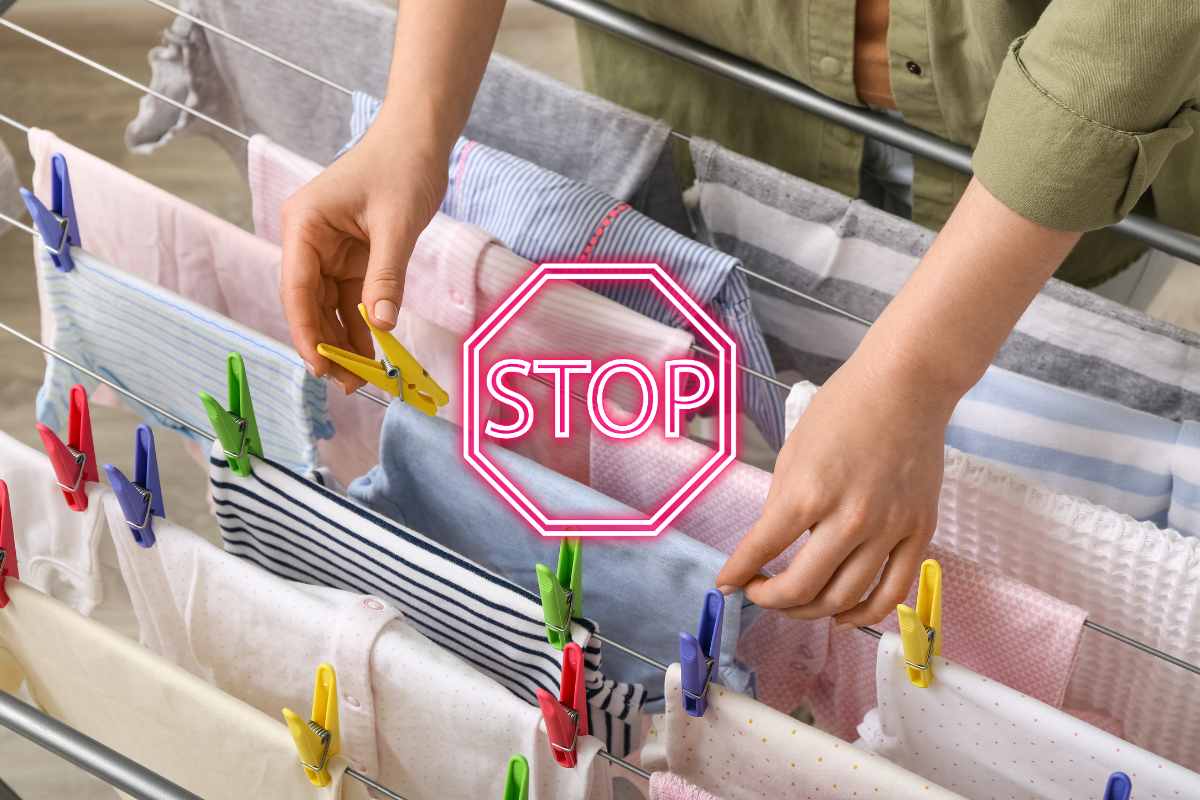 Una persona che appende il bucato sullo stendino ed un segnale di stop in primo piano