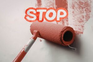 Un a persona che tinteggia il muro ed una scritta di "Stop"