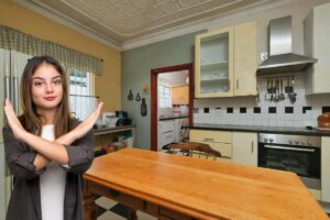 Una cucina con un tavolo ed una ragazza che fa cenno di disapprovazione