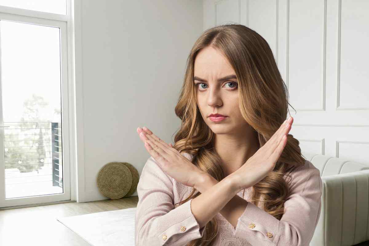 donna che dice di no con sfondo di un soggiorno con divano bianco