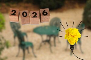 sedie e tavolino da esterno sfuocati con scritta 2026 e lampadina in primo piano