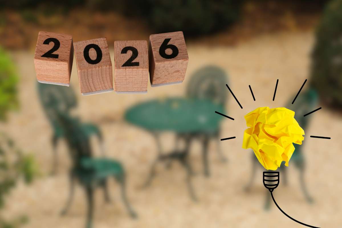 sedie e tavolino da esterno sfuocati con scritta 2026 e lampadina in primo piano