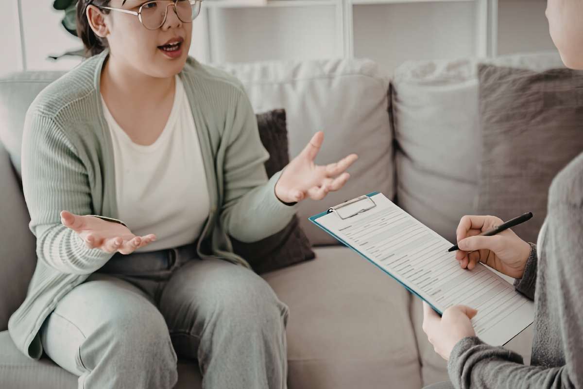 donna che parla con altra che ha cartellina in mano 