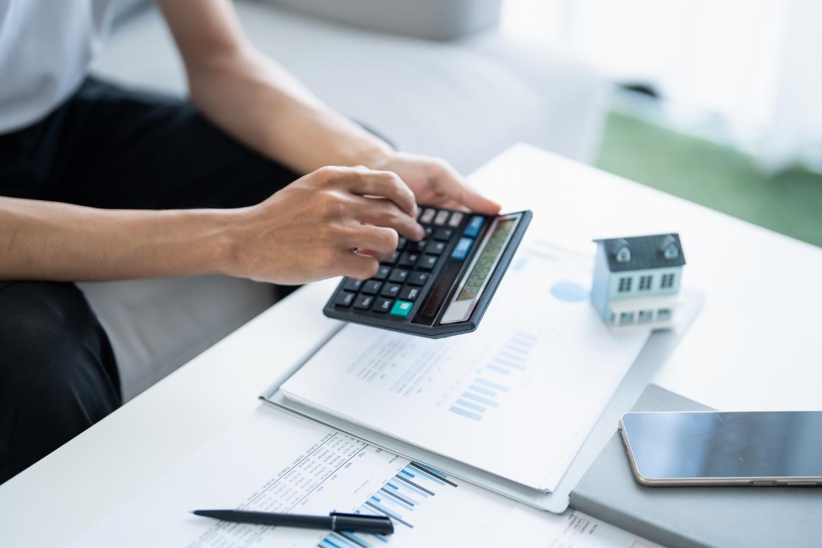 mano che fa conti sulla calcolatrice e fogli vari