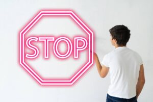 uomo che dipinge parete e scritta stop in rosso