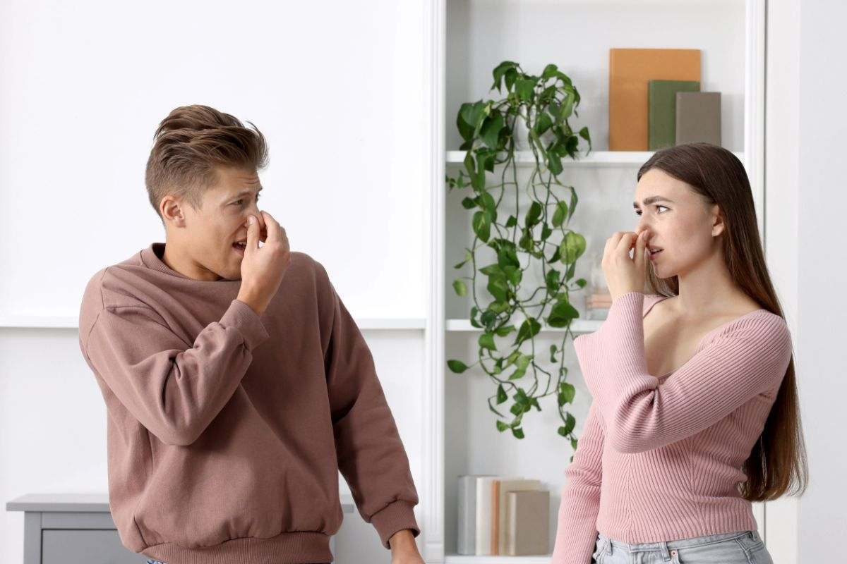 coppia di ragazzi che si tappa il naso in casa per il cattivo odore