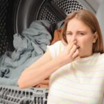 asciugatrice con panni alle spalle e donna che tiene il dito sul naso per cattivo odore