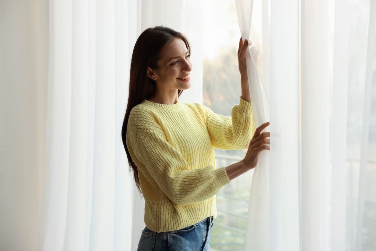 giovane donna che apre tenda di casa