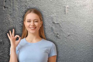 imperfezione su muro e donna che fa occhiolino ed ok con le mani