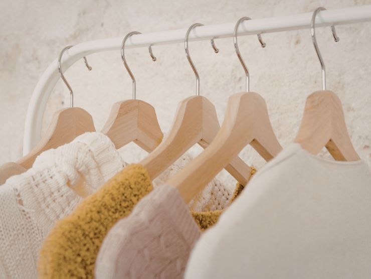 abiti appesi in un armadio con grucce in legno