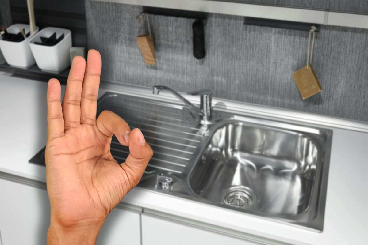 cucina con lavello in acciaio inossidabile e mano che fa ok