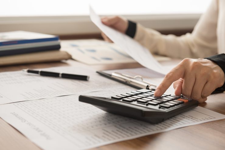 Una persona che fa dei conti con dei documenti ed una calcolatrice