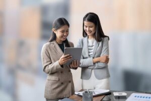 donne che parlano con fogli in mano e sfondo con piastrelle sfuocate