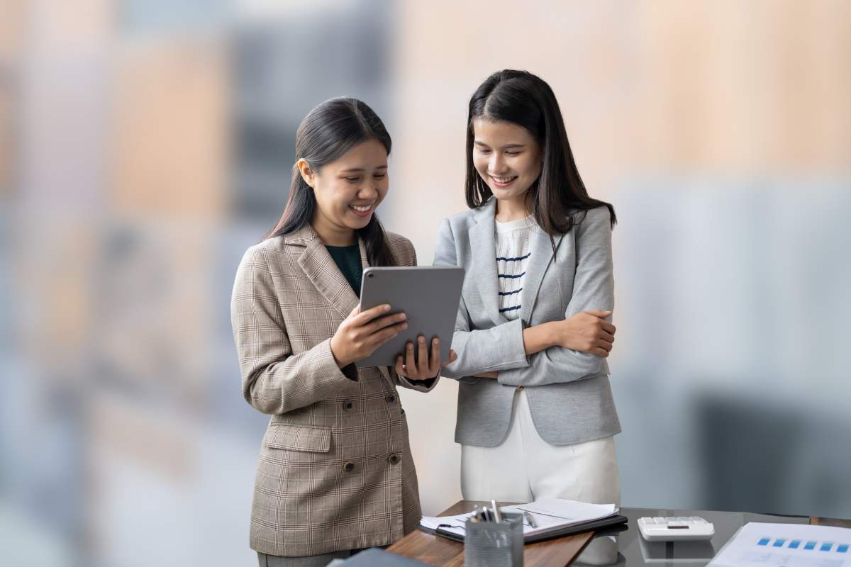 donne che parlano con fogli in mano e sfondo con piastrelle sfuocate