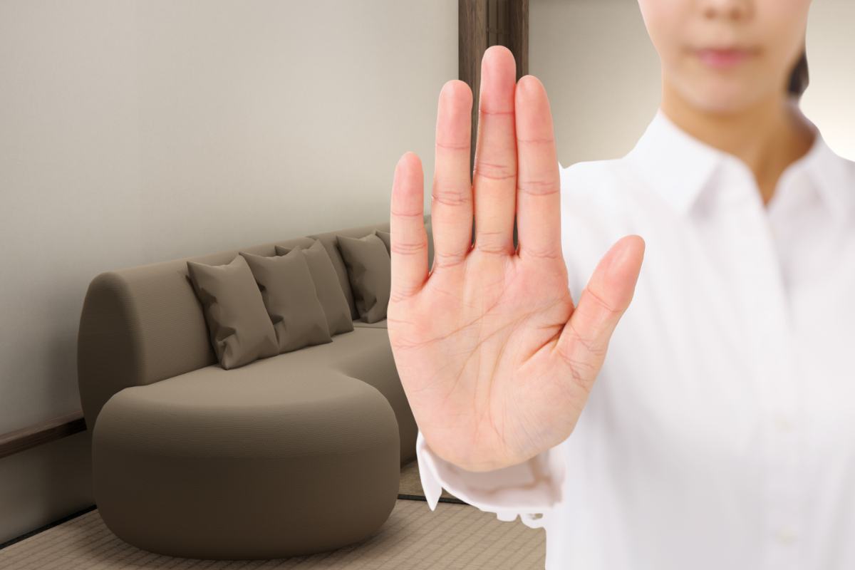 divano sullo sfondo e mano che fa segno stop