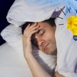uomo che dorme sotto le coperte con lampadina sulla destra per idea