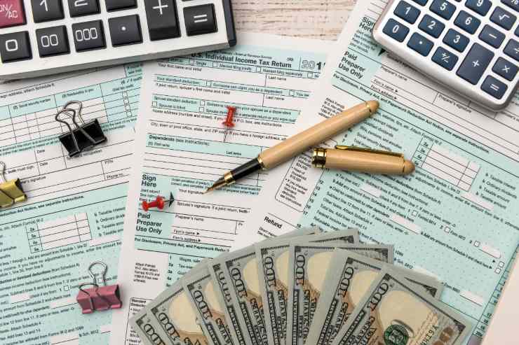 Diversi documenti fiscali con sopra soldi, penne e calcolatrice