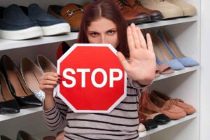 scarpiera sullo sfondo donna che fa segno di stop con mano e cartello