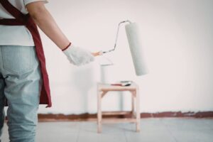 Un imbianchino con un rullo con davanti una parete bianca