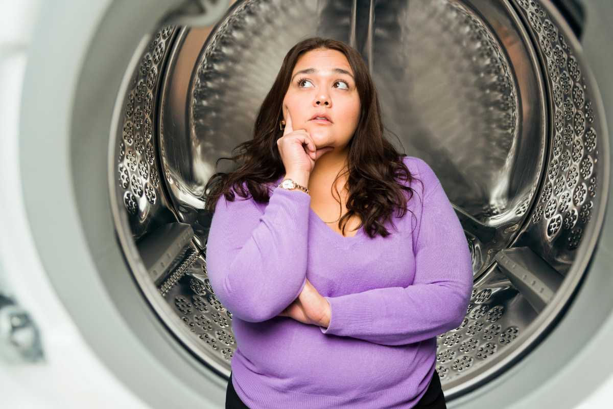 lavatrice con sportello aperto e donna che pensa ad una idea