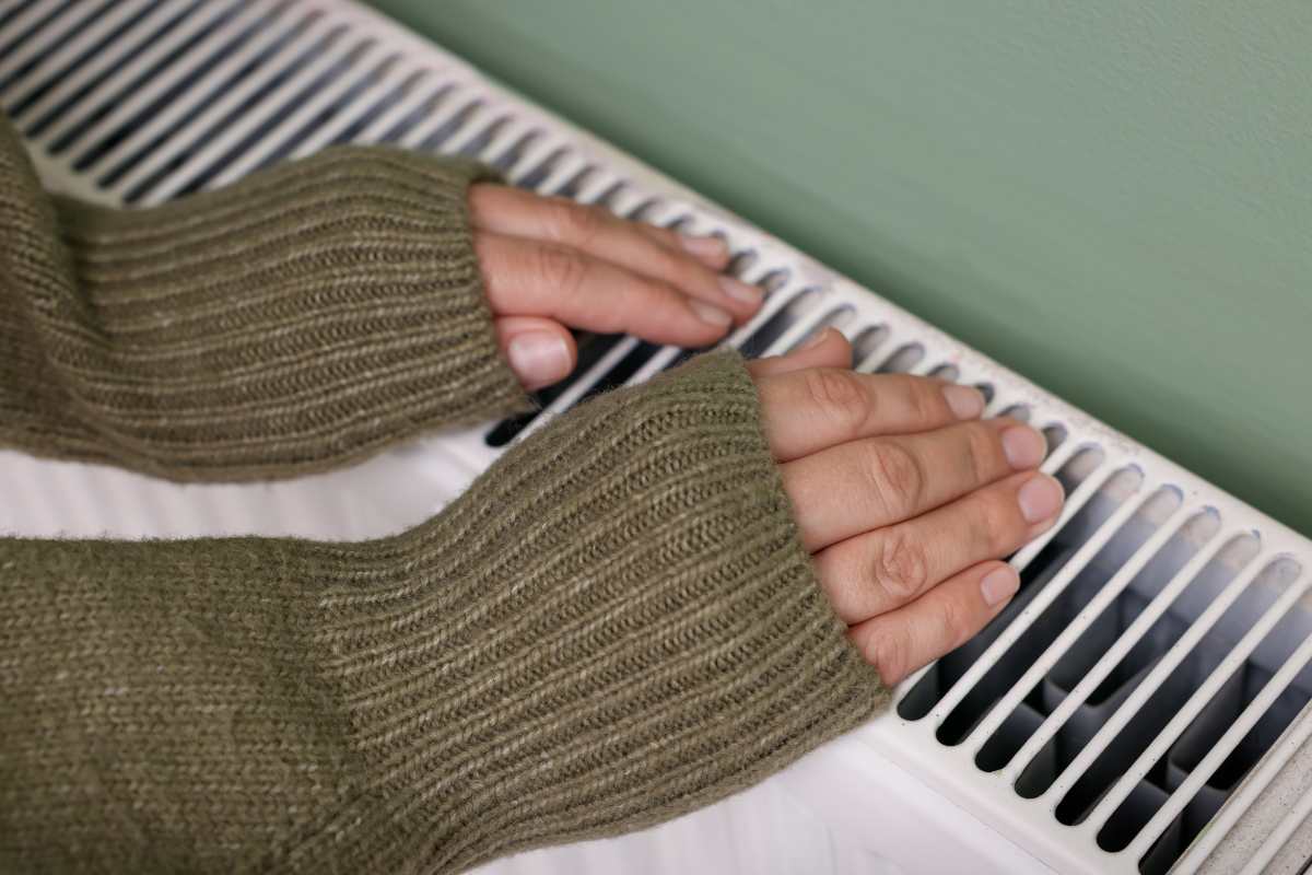 donna con mani sul termosifone 