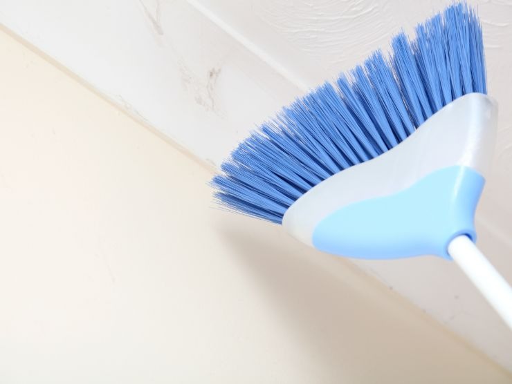scopa che passa sotto il soffitto per eliminare le ragnatele