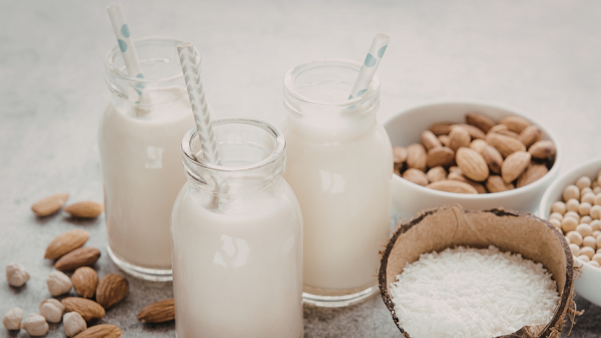 bottiglie di vetro con latte e frutta secca dentro ciotole 