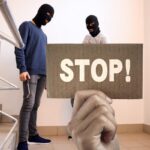 ladri sulle scale di casa e mano con cartello e scritta stop
