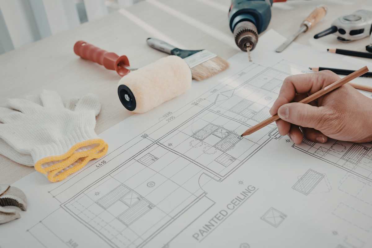 mani su progetto di ristrutturazione di una casa e oggetti del mestiere