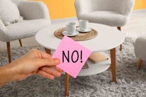 mano che mantiene un posti it con scritta no posta su un tavolino da caffè