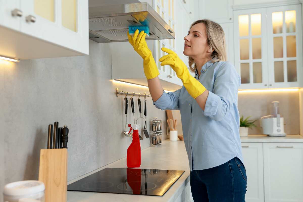 Donna con guanti che pulisce la cappa 