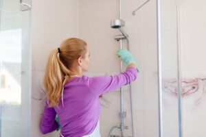 donna che pulisce il box doccia