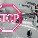 rubinetto con acqua che scorre e scritta stop in rosso