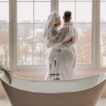 Una coppia entrambi in accappatoio che si abbraccia davanti ad una vasca da bagno
