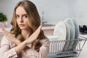 donna che fa segno di no con mani e scolapiatti sullo sfondo