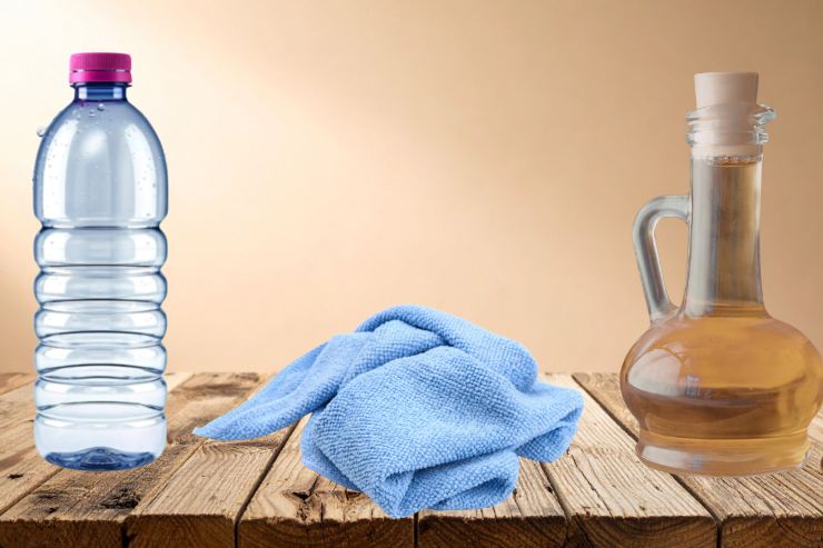 un tavolo con sopra un panno in microfibra, una bottiglia di aceto ed una bottiglia di acqua