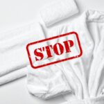 Degli asciugamani ed un accappatoio sul fondo ed una scritta di stop in primo piano