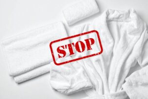 Degli asciugamani ed un accappatoio sul fondo ed una scritta di stop in primo piano