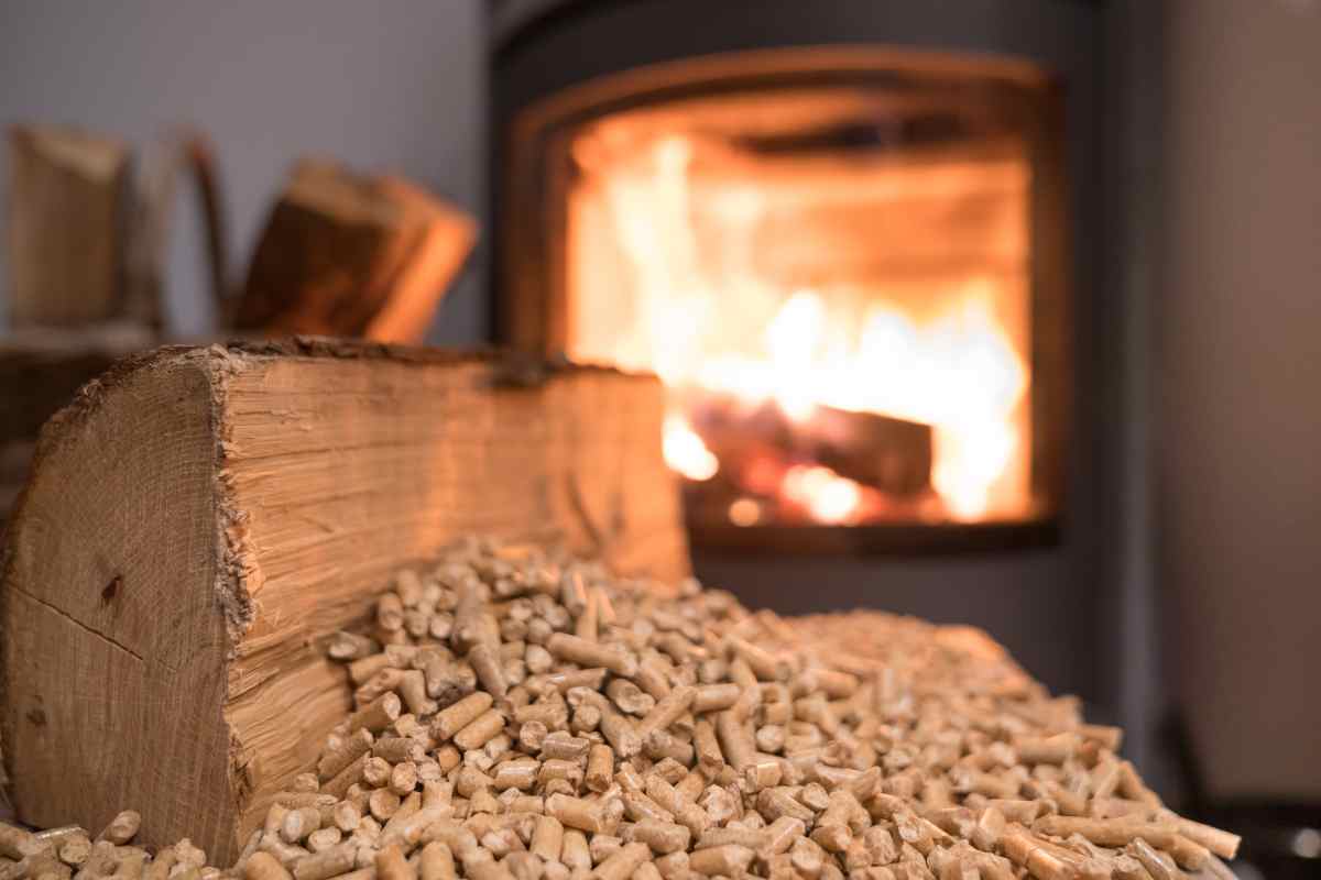 stufa a pellet sullo sfondo ed in primo piano pellet e tronco di legno 