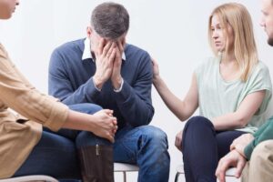 persone preoccupate e donna con mano su spalla dell'uomo