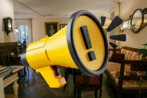 soggiorno con megafono giallo al centro e simbolo attenzione