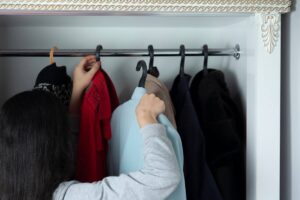 donna che sistema abiti nell'armadio