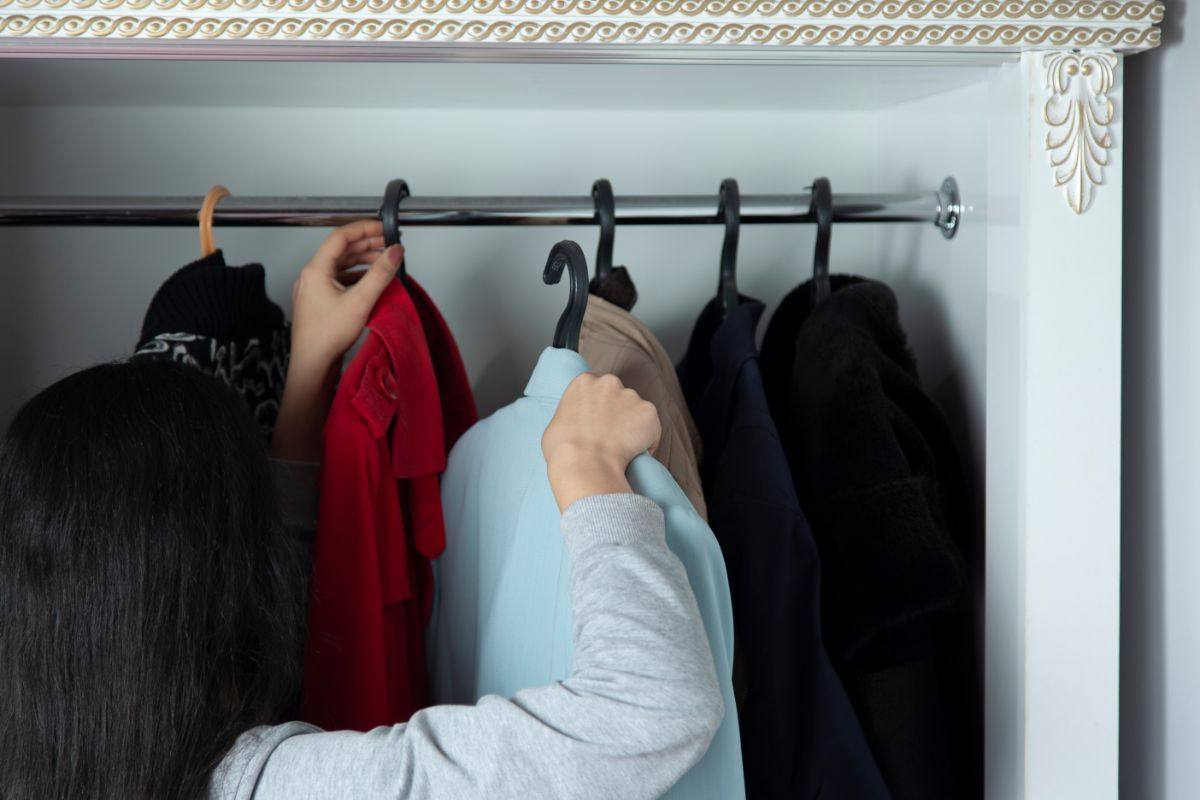 donna che sistema abiti nell'armadio