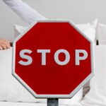 donna che rifa il letto e cartello rosso con scritto stop