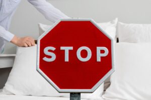 donna che rifa il letto e cartello rosso con scritto stop