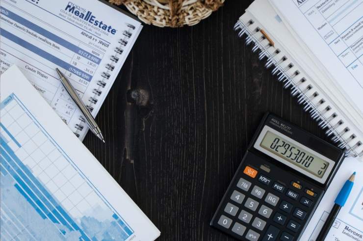 Dei documenti immobiliari ed una calcolatrice in primo piano