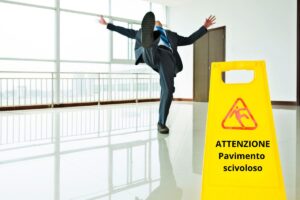 Un uomo che scivola su un pavimento bagnato ed un cartello in primo piano con sopra scritto "ATTENZIONE Pavimento scivoloso"