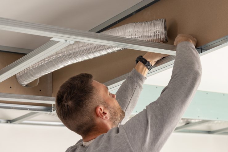 Un operaio che installa le tubazioni sul soffitto